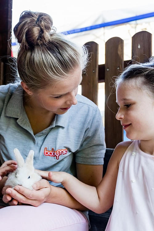 Betreuerin im Baby- & Kinderhotel Babymio zeigt einem Kind ein Kaninchen