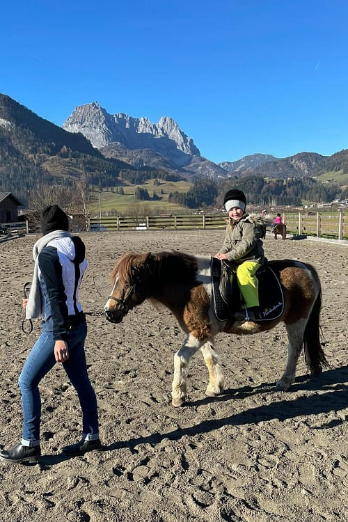 Kind reitet auf einem Pony vor herrlichen Bergkulisse in Tirol, Region Kitzbühel