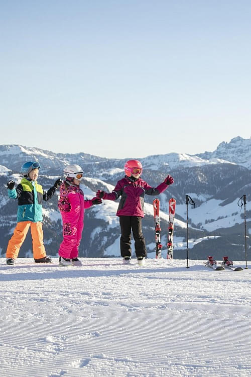 Kinder in Skiausrüstung im Skigebiet Kitzbühel in den Tiroler Alpen genießen den Schnee