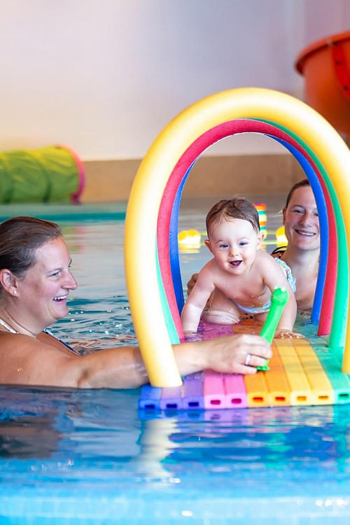 Eltern spielen mit Baby bzw. Kleinkind im Hallenschwimmbad des Hotel Babymio